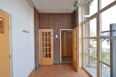 <p>In schoon metselwerk uitgevoerde scheidingswand tussen de gang en de aanbouw met de toiletten op de verdieping. De deuren dateren nog uit de bouwtijd. </p>
